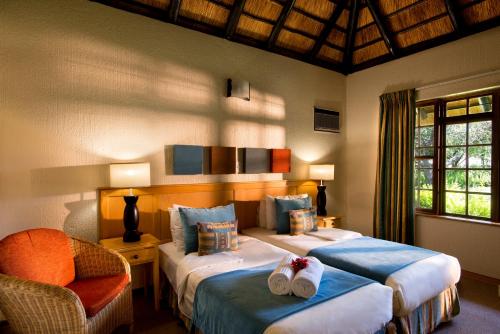a bedroom with two beds and a chair at Kruger Park Lodge in Hazyview