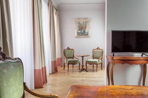 a room with a table and chairs and a television at Boutique Hotel Constans in Prague