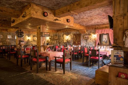 a restaurant with wooden walls and tables and red chairs at Hotel Crnogorska Kuća in Podgorica