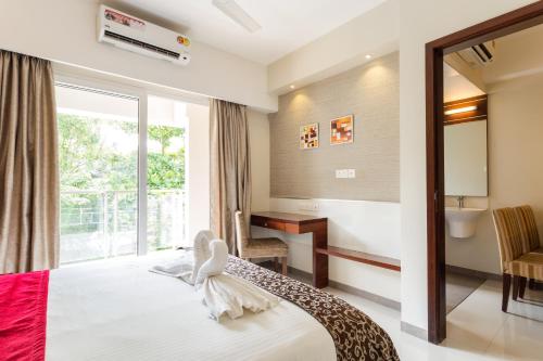 a bedroom with a bed and a window and a desk at D Homz Suites in Cochin