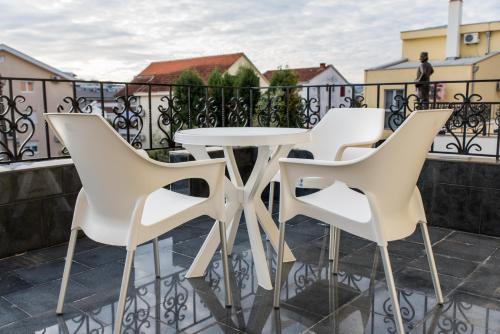 a white table and four white chairs on a balcony at Hotel Crnogorska Kuća in Podgorica