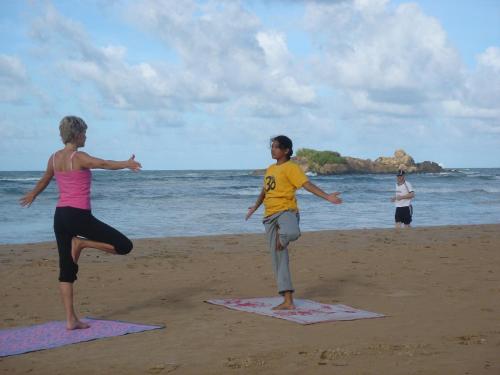 two girls are practicing yoga on the beach at Muthumuni Ayurveda Beach Resort in Beruwala
