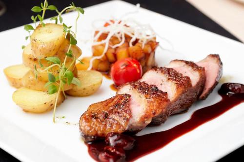 a white plate of food with meat and vegetables at Hotel NockResort in Bad Kleinkirchheim