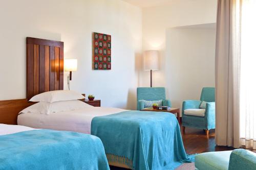 une chambre d'hôtel avec deux lits et deux chaises dans l'établissement Pousada Castelo de Alcacer do Sal, à Alcácer do Sal