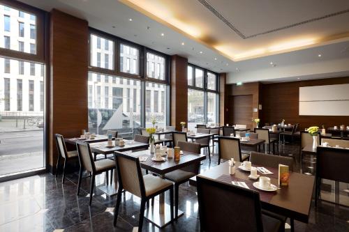 a restaurant with tables and chairs and windows at Eurostars Berlin in Berlin