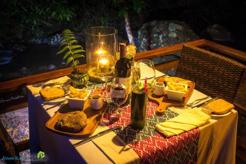 a table with food and wine glasses on it at Namkat Yorla Pa Resort in Ban Kat