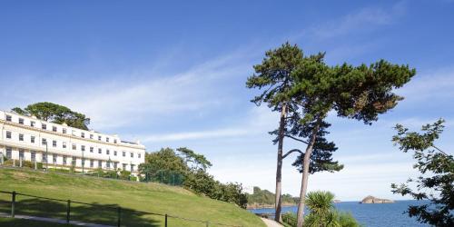 a building on a hill next to a body of water at The Osborne Apartments in Torquay