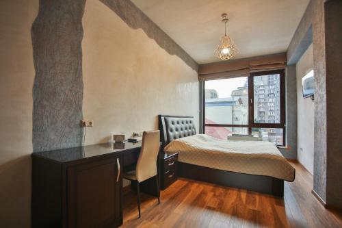 a bedroom with a bed and a desk and a window at Hotel Wine Palace in Tbilisi City