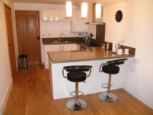 eine Küche mit einer Theke und 2 Barhockern in der Unterkunft Higher Greenway Annexe in Brixham