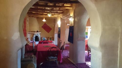 una sala da pranzo con tavolo e sedie rossi di Riad Auberge Bassou a Nkob