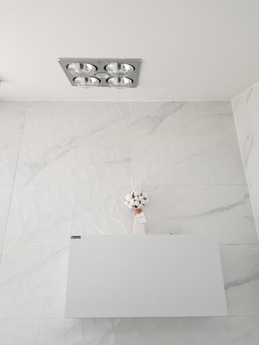 a bathroom with white marble floors and a vase of flowers at HANI Haus in Jeju