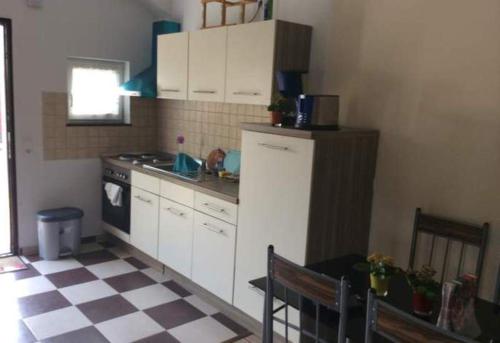 eine Küche mit weißen Schränken und einem karierten Boden in der Unterkunft Ferienhaus Mockritz in Dresden