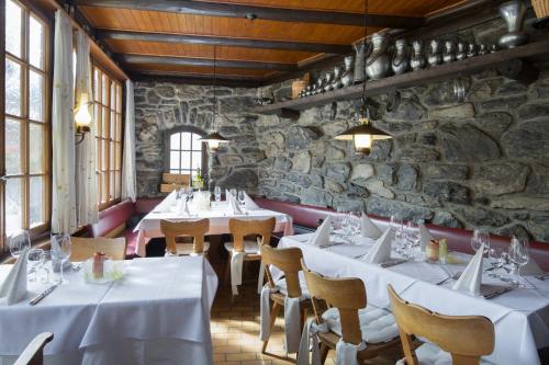 a restaurant with white tables and chairs and a stone wall at Hotel Blumental in Mürren