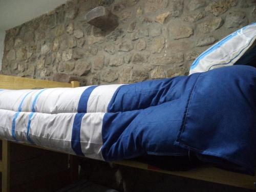 a bed with a blue and white blanket on it at Gringo's Wasi in Cusco
