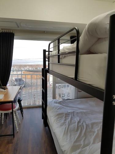 two bunk beds in a room with a desk and a balcony at HANI Haus in Jeju