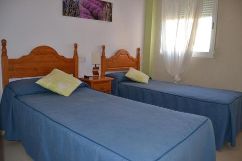 デニアにあるFaro 2 Locdeniaのベッドルーム1室(青いシーツと窓付きのベッド2台付)