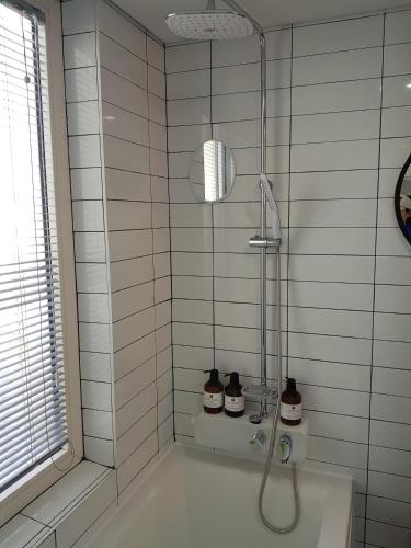a shower in a white tiled bathroom with a tub at HANI Haus in Jeju
