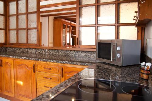 a kitchen with wooden cabinets and a microwave at Casa Pintor in Sant Sadurní dʼAnoia