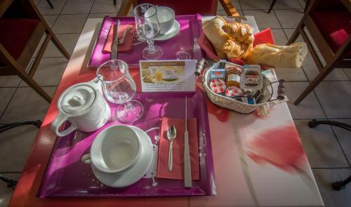 einen Tisch mit einem lila Tablett mit Tellern und Weingläsern in der Unterkunft Hotel Restaurant Le Castel Fleuri in Carnoules