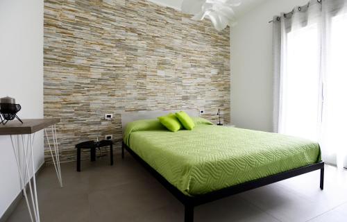 サン・ヴィート・ロ・カーポにあるMira7のレンガの壁のベッドルーム1室(緑のベッド1台付)
