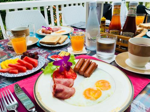 a table with a plate of breakfast foods and drinks at Baan Ing Khao in Pak Chong