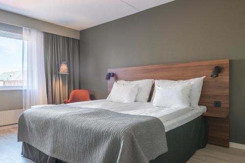 a bedroom with a large bed with a wooden headboard at Quality Hotel Grand Kristianstad in Kristianstad