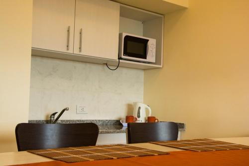 a kitchen with two chairs and a microwave at Rio Manso Apartamentos in Victoria