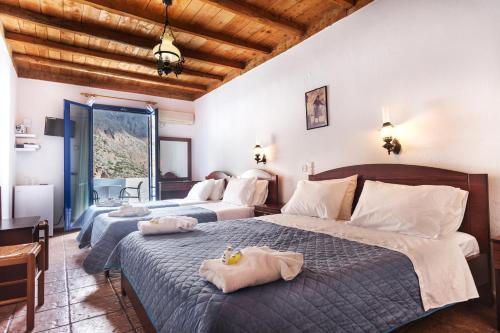 
a bedroom with a large bed and a large window at Daskalogiannis Hotel in Loutro
