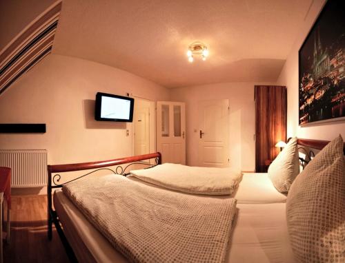 a bedroom with two beds and a flat screen tv at Balthasar Neumann Speiserei & Gästehaus - Zentrum Brühl -E-Ladestation, nähe Phantasialand in Brühl