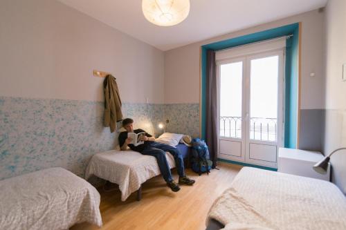 a man sitting on a bed in a room at Onefam Sungate in Madrid