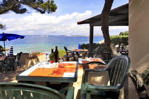 an outdoor table with chairs and a view of the ocean at Grand Hotel Smeraldo Beach in Baja Sardinia