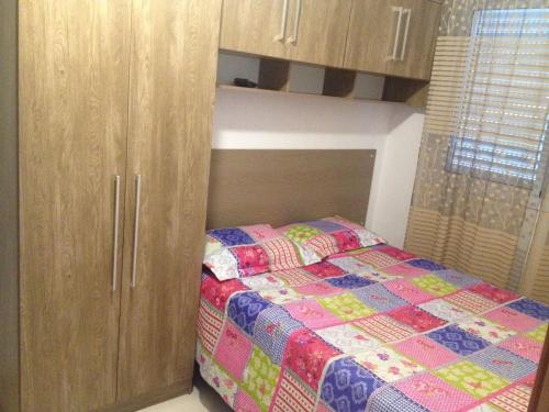 a small bedroom with a bed and wooden cabinets at Apartamento Praia Grande in Praia Grande