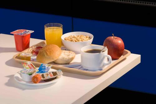 a tray of breakfast food with an apple and a cup of coffee at Caramel Hotels in Bangalore