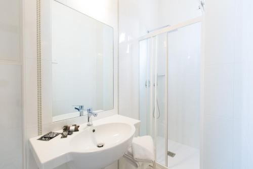 a white bathroom with a sink and a shower at Hotel Confort in Cattolica
