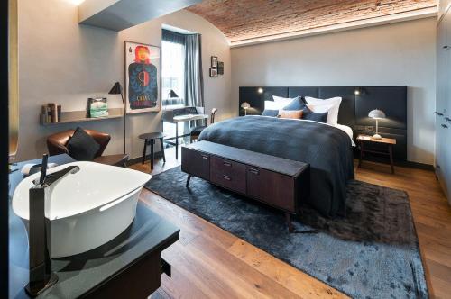 a bedroom with a bed and a tub and a sink at Hotel Liberty Offenburg in Offenburg