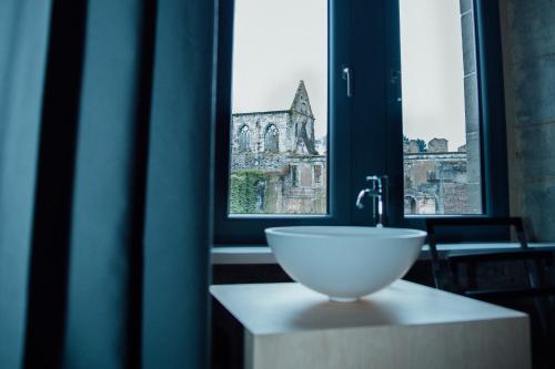 eine Schüssel mit Spüle auf einer Theke vor einem Fenster in der Unterkunft Auberge de l'Abbaye in Thuin