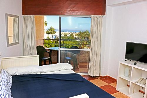 ベナルマデナにあるApartamentos Tamarindosのベッドと大きな窓が備わるホテルルームです。