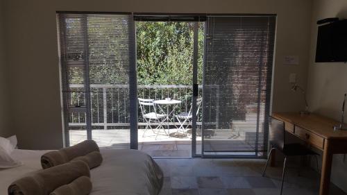 a bedroom with a bed and a sliding glass door at Orangerie Guest House in Johannesburg