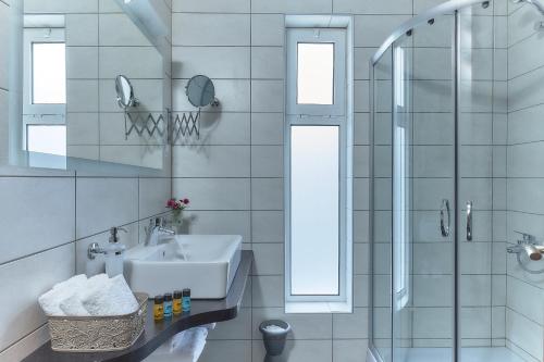 a white bathroom with a sink and a shower at Nymphes Luxury Apartments in Agia Pelagia