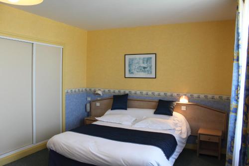 a bedroom with a large bed with yellow walls at Hotel Des Bains in Lancieux