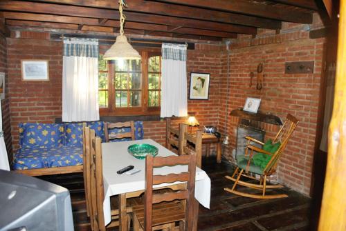 a dining room with a table and chairs and a brick wall at Cabañas Poetas del Bosque in Mar Azul