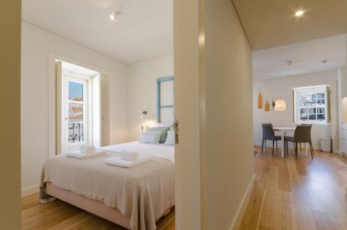 a white bedroom with a bed and a dining room at Casas da Baixa - dAmouraria in Lisbon