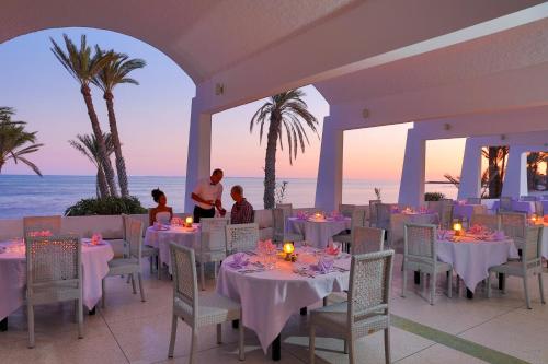 a restaurant on the beach with tables and chairs at Hari Club Beach Resort in Aghīr