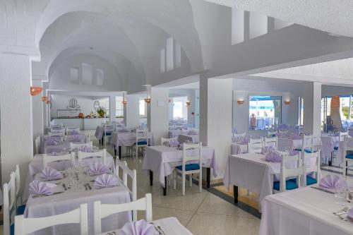 a dining room with white tables and purple chairs at Hari Club Beach Resort in Aghīr