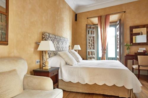 a bedroom with a large white bed and a chair at Hotel Boutique Corral del Rey in Seville