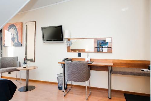 a room with a desk and a tv on a wall at Home Hotel Kung Oscar in Trollhättan