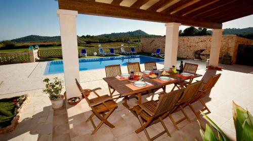 プレラスにあるQuality Villa Sa Tapiaの木製テーブルと椅子、プール付きのパティオ