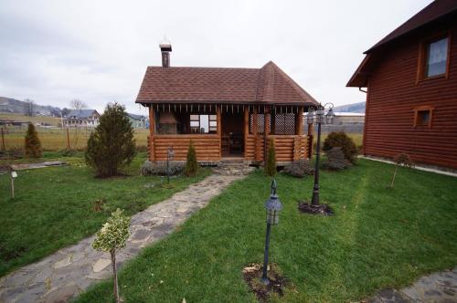 a log cabin with a porch in a yard at Panorama Yasinya in Yasinya