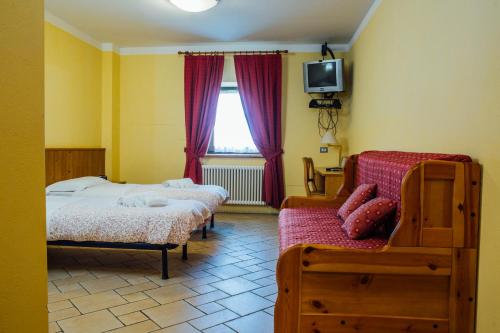 1 dormitorio con 2 camas, sofá y TV en Albergo Ristoro Sitten en Gressoney-la-Trinité
