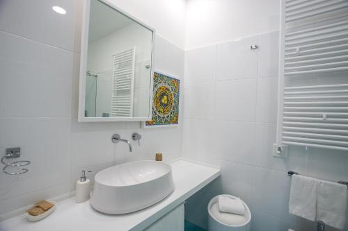 a white bathroom with a sink and a mirror at Tra Le Braccia di Morfeo in Terrasini